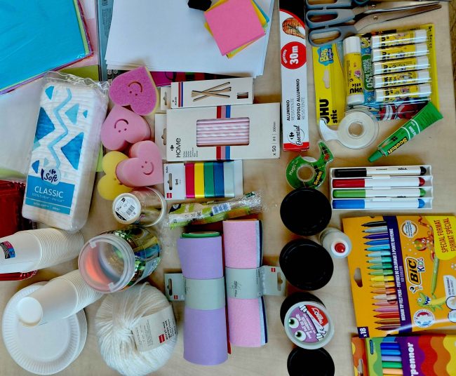 A table filled with lo-fi prototyping material such as coloured paper, pens, scissors, and sponges.