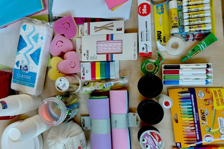 A table filled with lo-fi prototyping material such as coloured paper, pens, scissors, and sponges.
